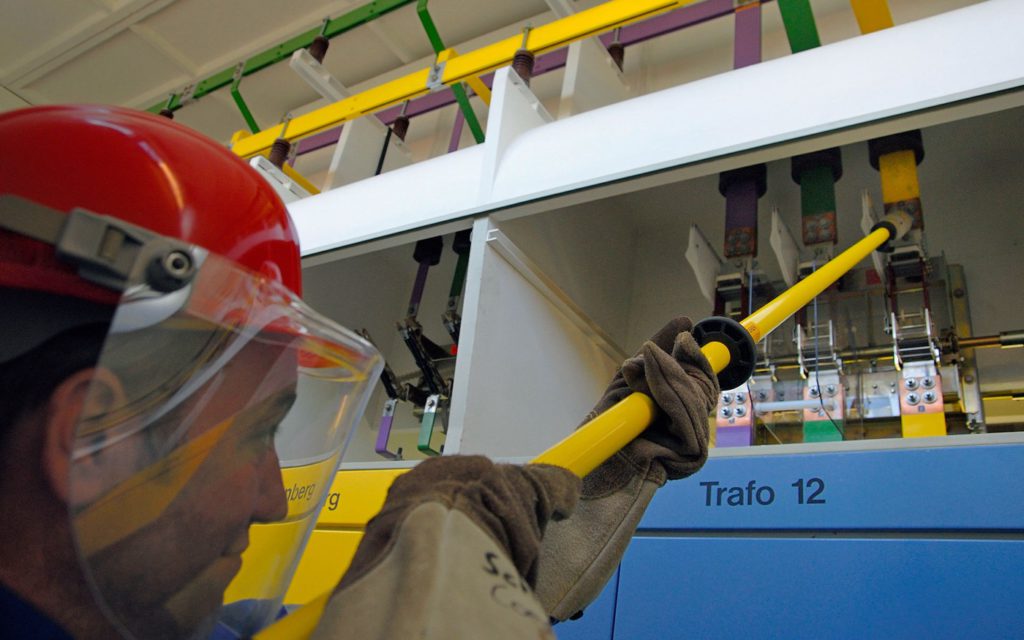 Mann mit Schutzausrüstung arbeitet an einem Trafo Schrank